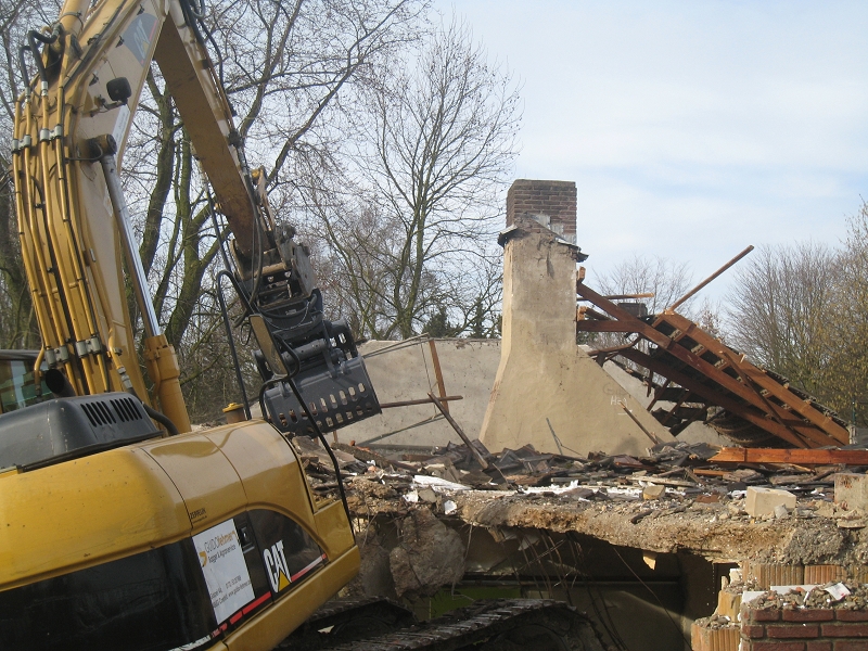 Kettenbagger mit Sortiergreifer und Wassersprühdüse beim Rückbau eines Gebäudes